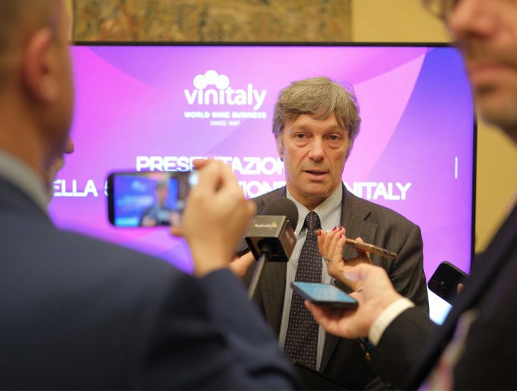 Intervista durante la presentazione di Vinitaly 2026 con logo sullo sfondo e media presenti