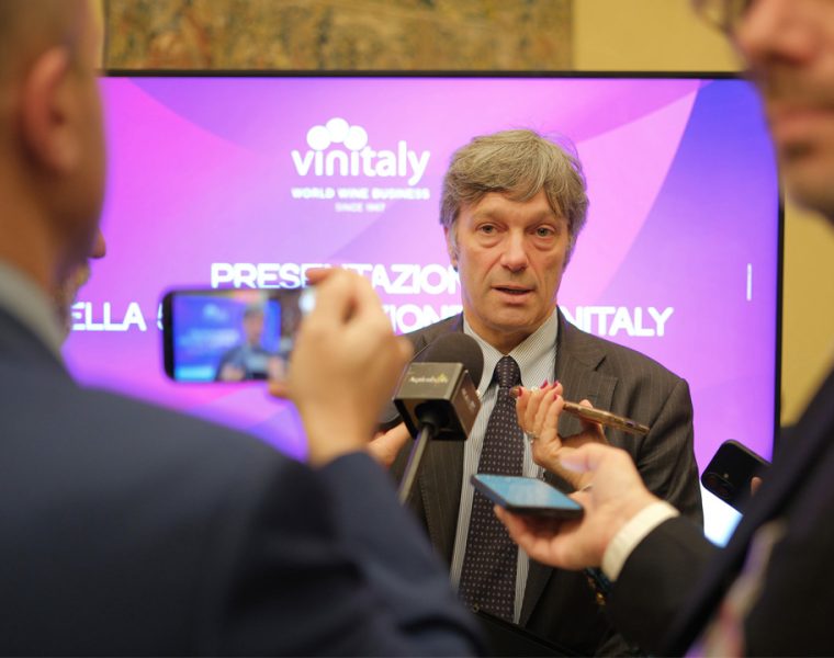 Intervista durante la presentazione di Vinitaly 2026 con logo sullo sfondo e media presenti