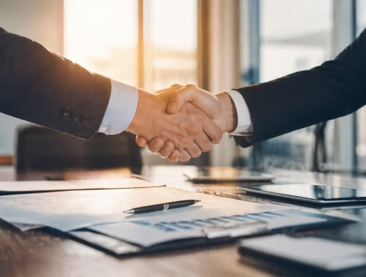 Acquisizione italiana azienda tedesca rappresentata da stretta di mano tra manager in contesto aziendale