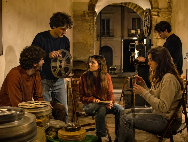 Giovani appassionati di cinema riuniti tra bobine e proiettore in un cineclub d’epoca