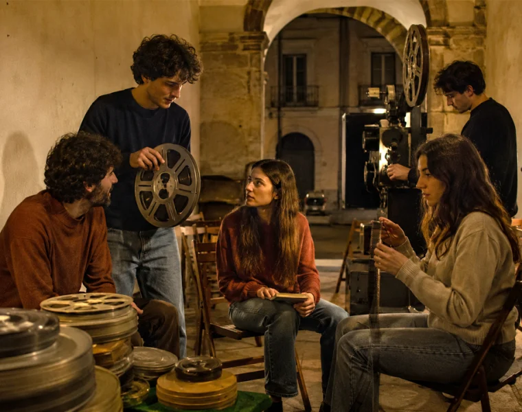 Giovani appassionati di cinema riuniti tra bobine e proiettore in un cineclub d’epoca