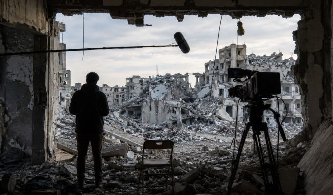 Venice4Palestine boicottaggio cinema italiano, scena cinematografica tra rovine urbane e telecamera.